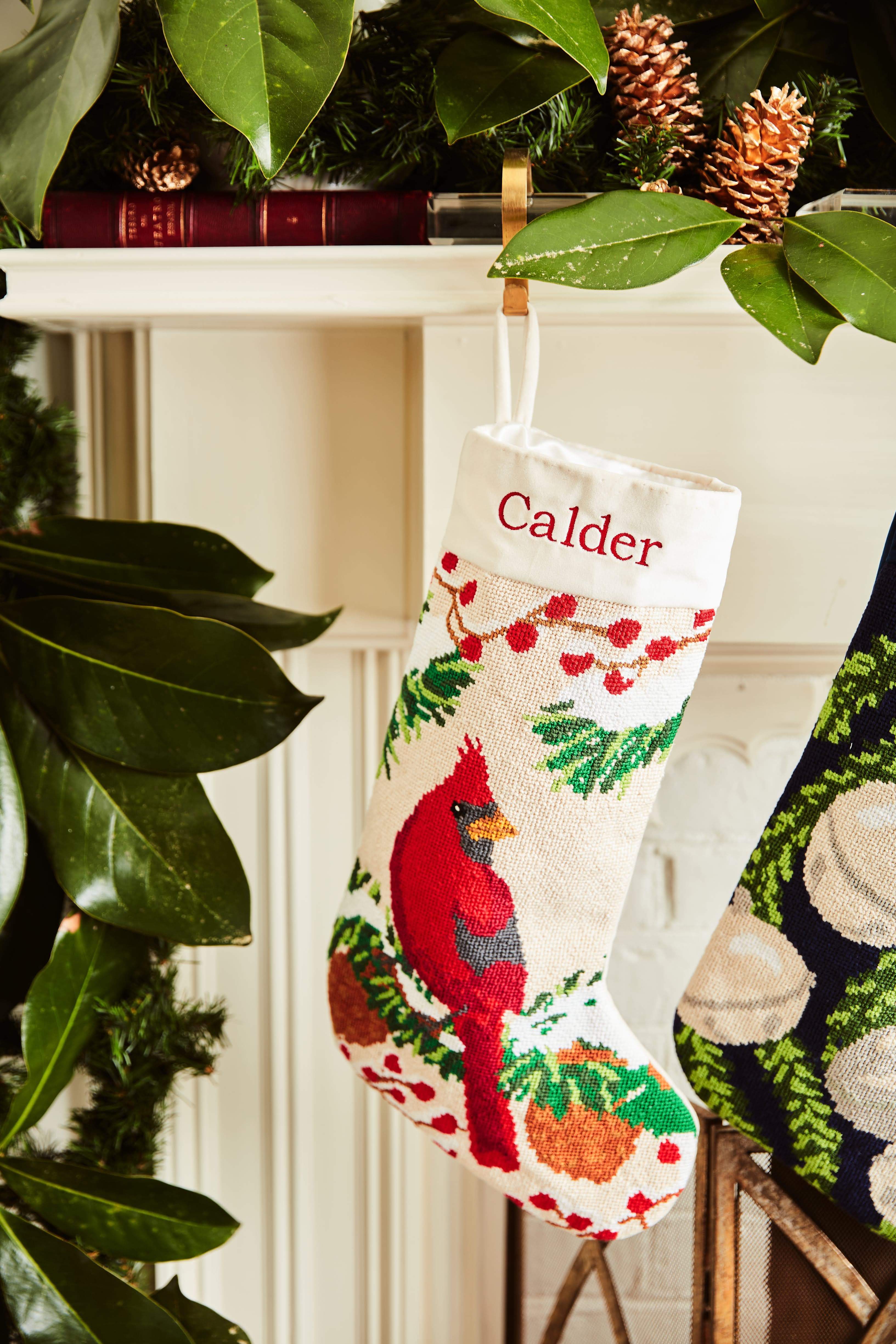 Full-size Christmas stocking with a monogrammed name in block featuring a red cardinal perched among holly, pinecones, and festive greenery