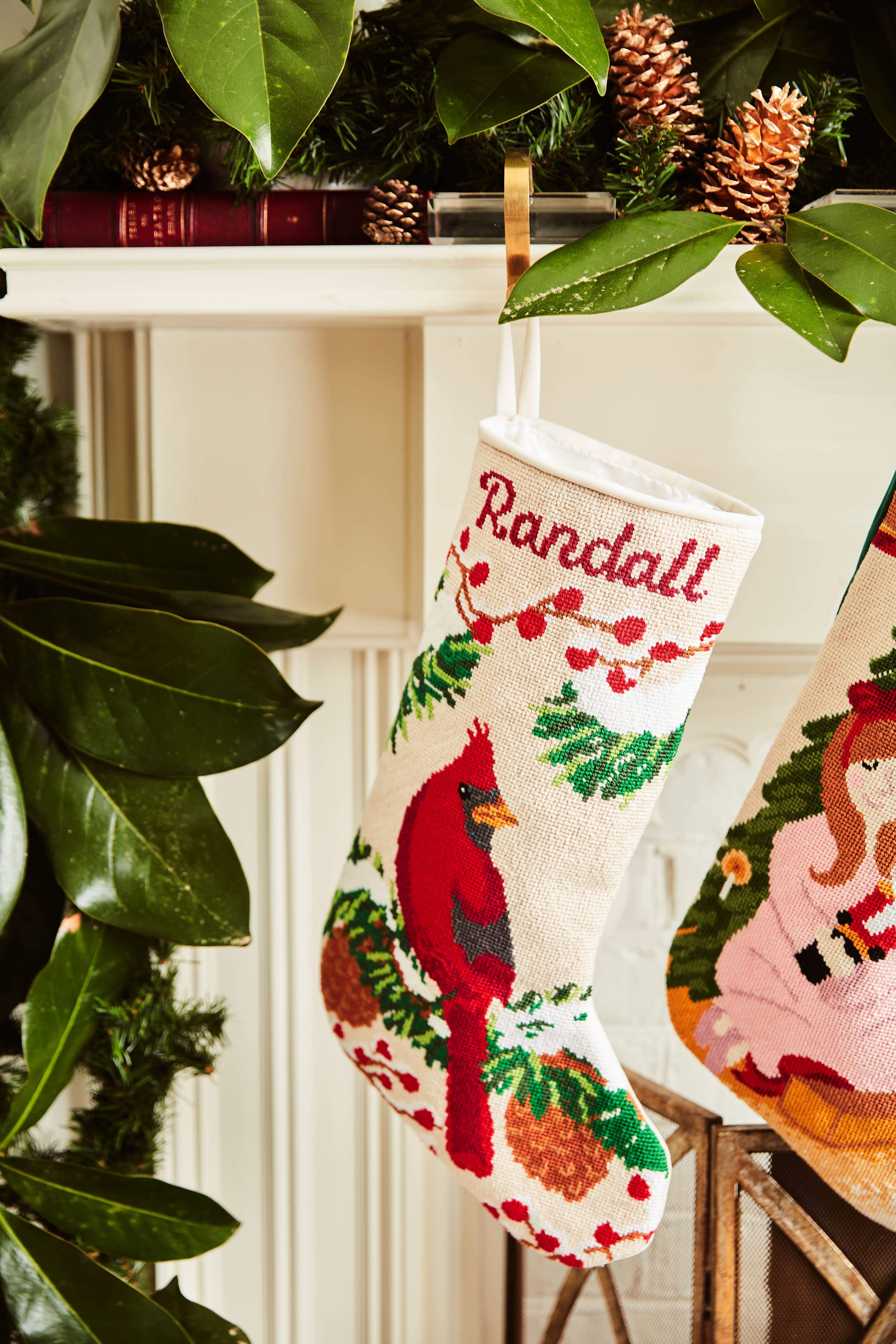 Full-size Christmas stocking with a monogrammed name in script featuring a red cardinal perched among holly, pinecones, and festive greenery