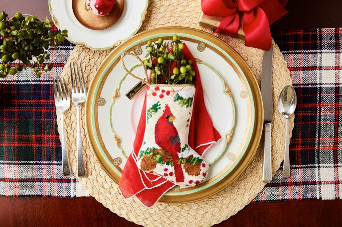 Flatlay featuring Christmas Cardinal stocking and ornament on red plaid background