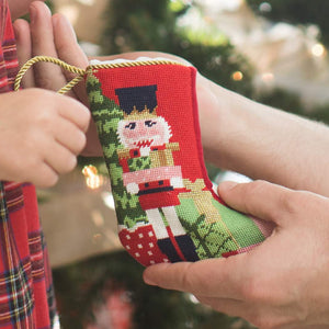 Man and young girl exchanging a gift in front of a decorated Christmas tree.