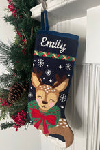 Full-size Christmas stocking with a monogrammed name in script featuring Dasher wearing a festive red bow and a green wreath around its neck on a navy blue backdrop with snowflakes