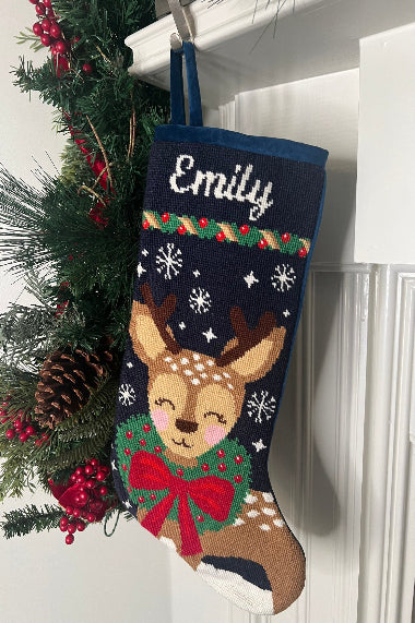 Full-size Christmas stocking with a monogrammed name in script featuring Dasher wearing a festive red bow and a green wreath around its neck on a navy blue backdrop with snowflakes