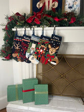 Festive mantle decorated with a Full Size Stockings, greenery, and holiday ornaments