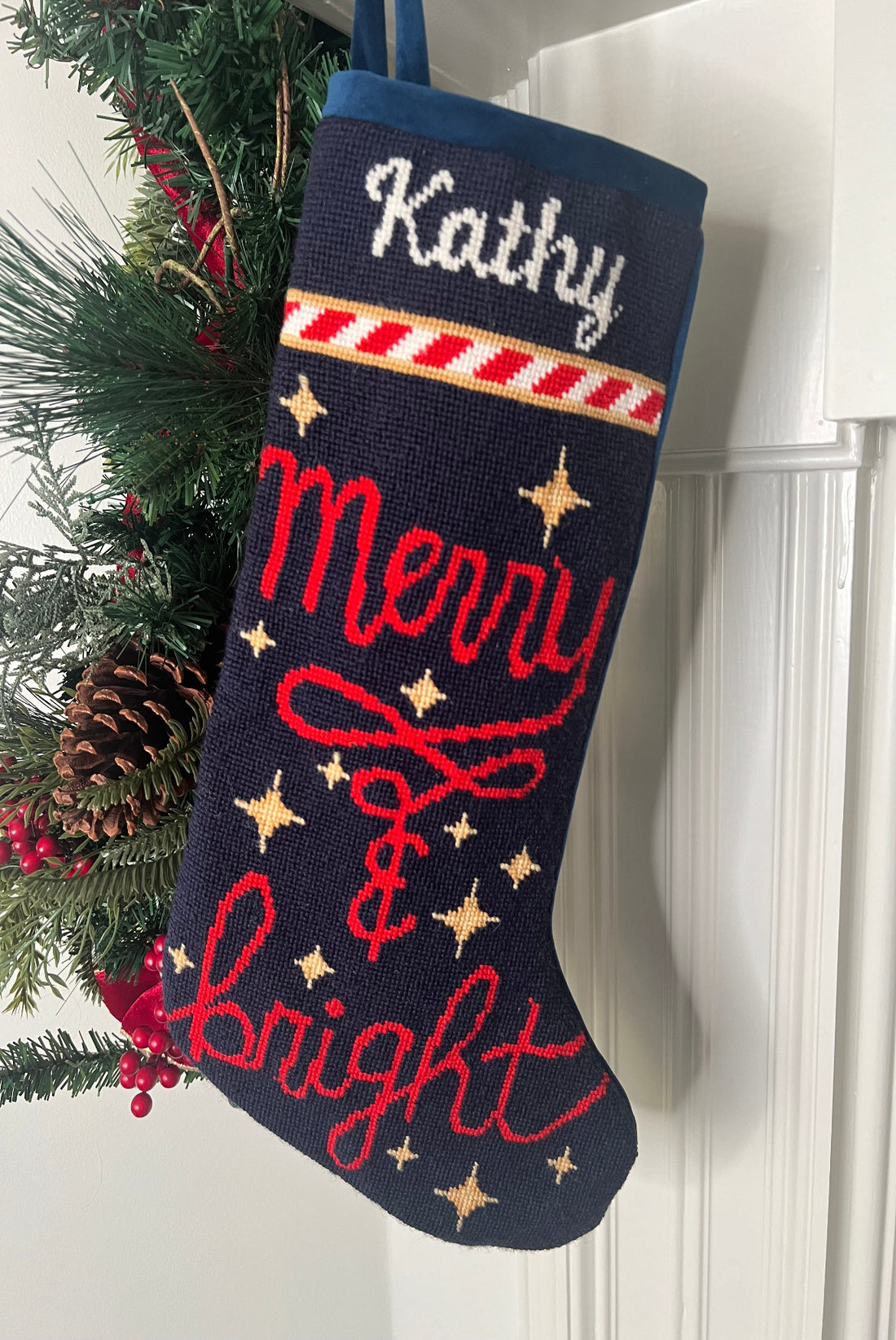 Full-size Christmas stocking with a monogrammed name in script featuring the Merry &amp; Bright in bold red lettering, adorned with twinkling golden stars on a navy blue background