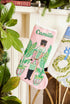 Full-size Christmas stocking with a monogrammed name in script featuring a vibrant nutcracker with festive details and palm accents on pink background