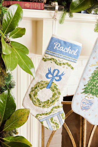 Full-size Christmas stocking with a monogrammed name in script featuring a festive wreath and ornaments design on white backdrop