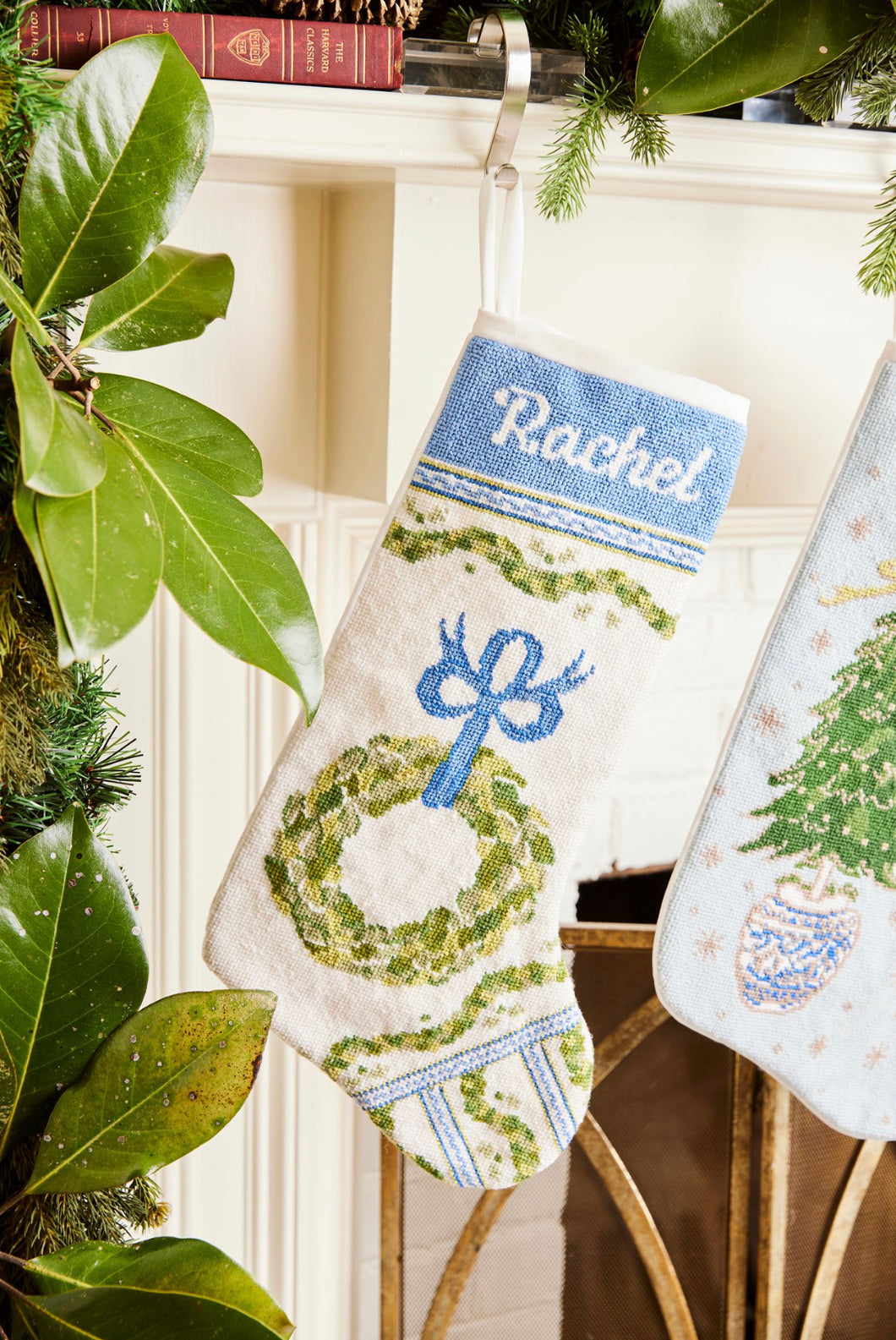 Full-size Christmas stocking with a monogrammed name in script featuring a festive wreath and ornaments design on white backdrop