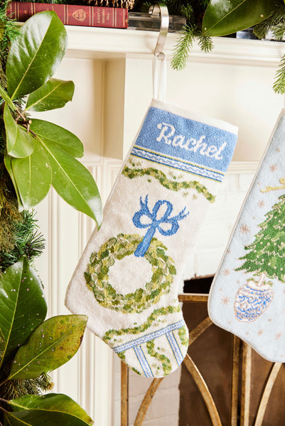 Full-size Christmas stocking with a monogrammed name in script featuring a festive wreath and ornaments design on white backdrop