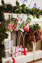 Festive mantle decorated with a Full Size Stockings, greenery, and holiday ornaments