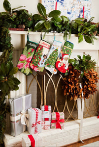 Festive mantle decorated with a Full Size Stockings, greenery, and holiday ornaments