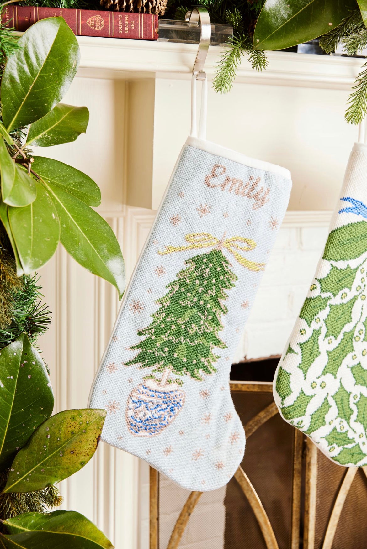 Full-size Christmas stocking with a monogrammed name in script featuring a vibrant, hand-stitched Christmas tree adorned with glittering ornaments on a soft light blue background