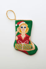 Needlepoint Bauble Stockings with festive Mrs. Claus design in red holiday outfit on green background