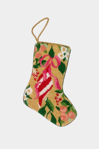 Needlepoint stocking featuring a red and white striped candy cane tied with a pink bow surrounded by holiday florals on a golden yellow background