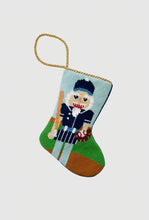 Needlepoint stocking featuring baseball nutcracker holding bat, glove, and ball on green field