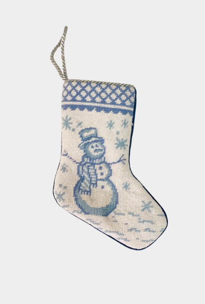 Needlepoint stocking featuring a blue snowman surrounded by falling snowflakes with decorative border