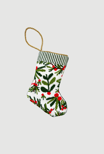 Needlepoint Christmas stocking featuring holiday greenery, red berries, and pine sprigs on white background