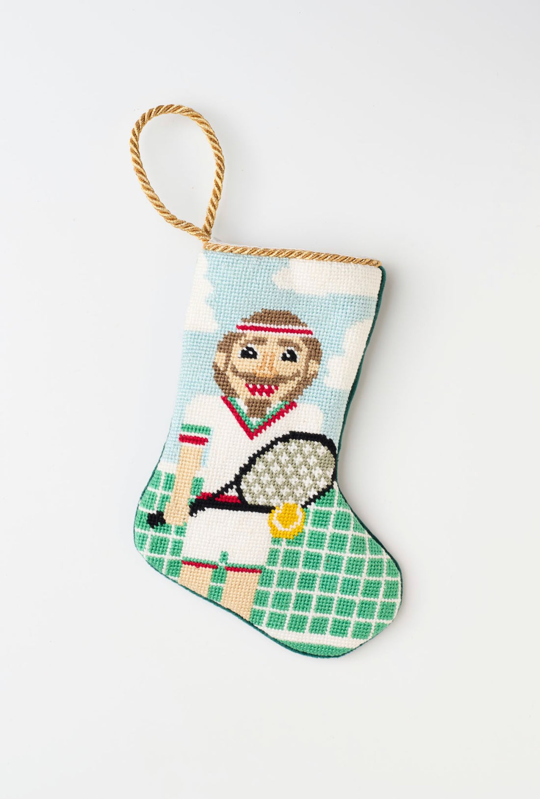 Needlepoint stocking featuring tennis nutcracker in tennis attire and holding racket on green court background.
