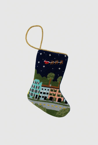 Hand-stitched Christmas stocking featuring Charleston’s Rainbow Row under a starry sky with Santa’s sleigh overhead