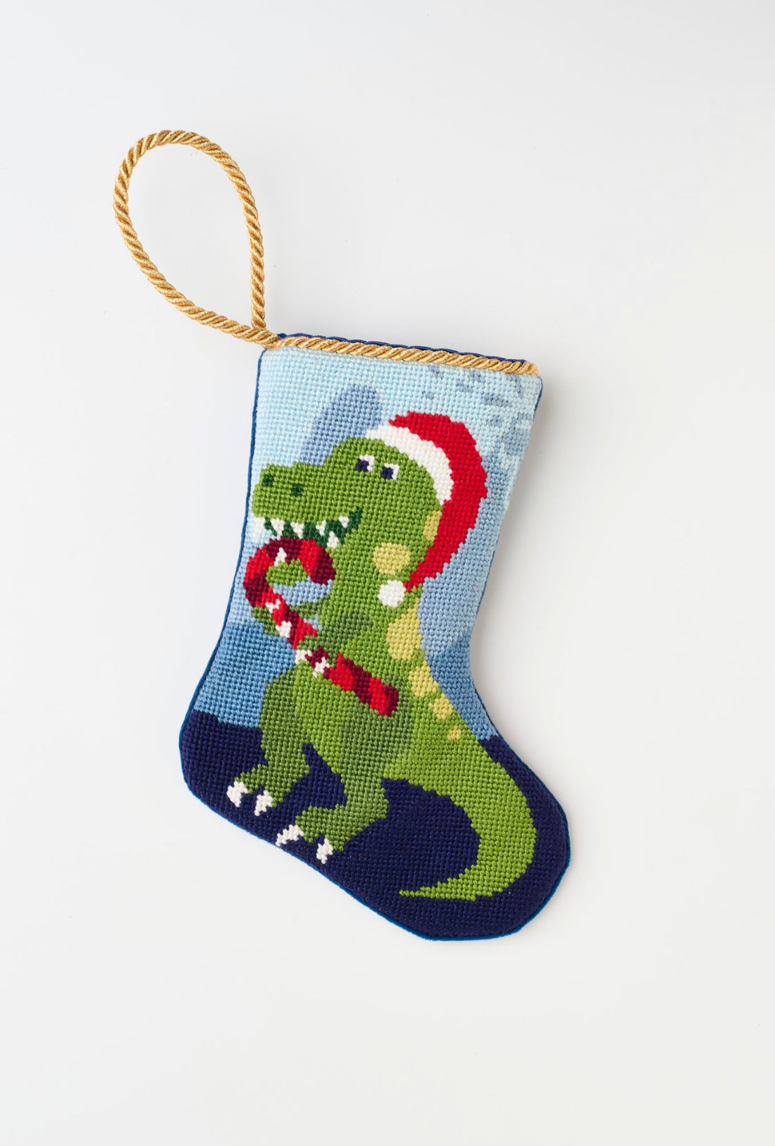 Needlepoint stocking featuring a dinosaur holding a candy cane and wearing a Santa hat
