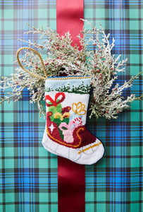 Christmas needlepoint stocking displayed with holiday decoration and festive greenery