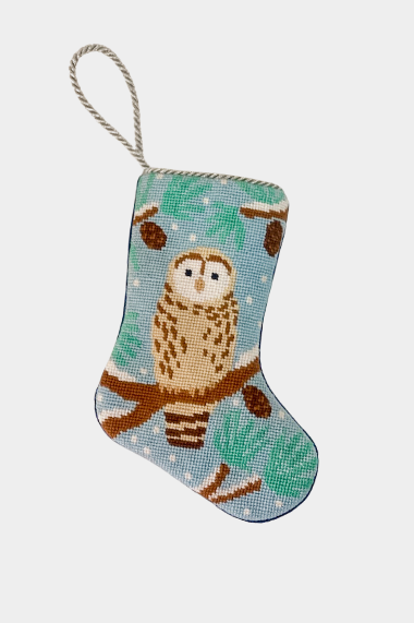 Hand-stitched needlepoint stocking featuring a snow owl perched on a pine branch with pinecones, against a wintry light blue background