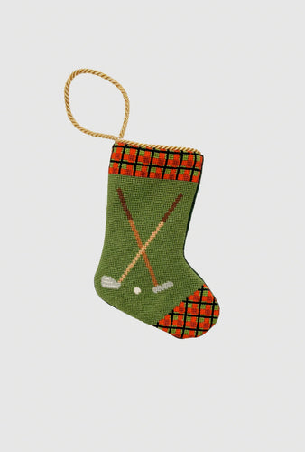 Needlepoint stocking with golf clubs, golf ball, and red plaid cuff on green background