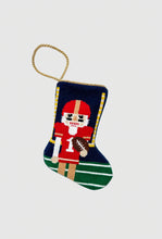 Hand-stitched stocking featuring football nutcracker in red uniform on green field background