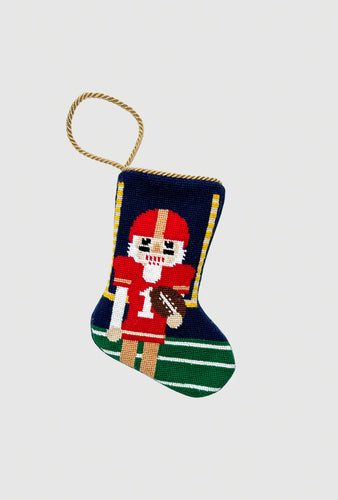 Hand-stitched stocking featuring football nutcracker in red uniform on green field background