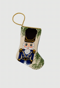 Handmade needlepoint stocking featuring a nutcracker in blue uniform with gold details and festive green accents