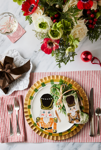 Holiday-themed table styled with Bauble Stockings, nutcracker plate, festive greenery, and red decor accents