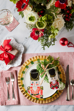 Holiday-themed table styled with Bauble Stockings, nutcracker plate, festive greenery, and red decor accents