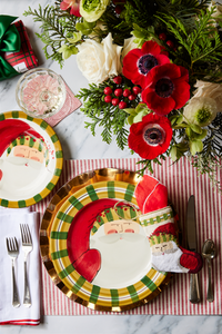 Christmas table styled with Bauble Stockings, greenery, Santa plates, and festive red decor