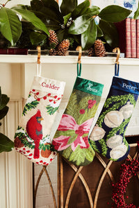 Festive mantle decorated with a Full Size Stockings, greenery, and holiday ornaments