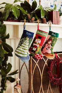 Festive mantle decorated with a Full Size Stockings, greenery, and holiday ornaments