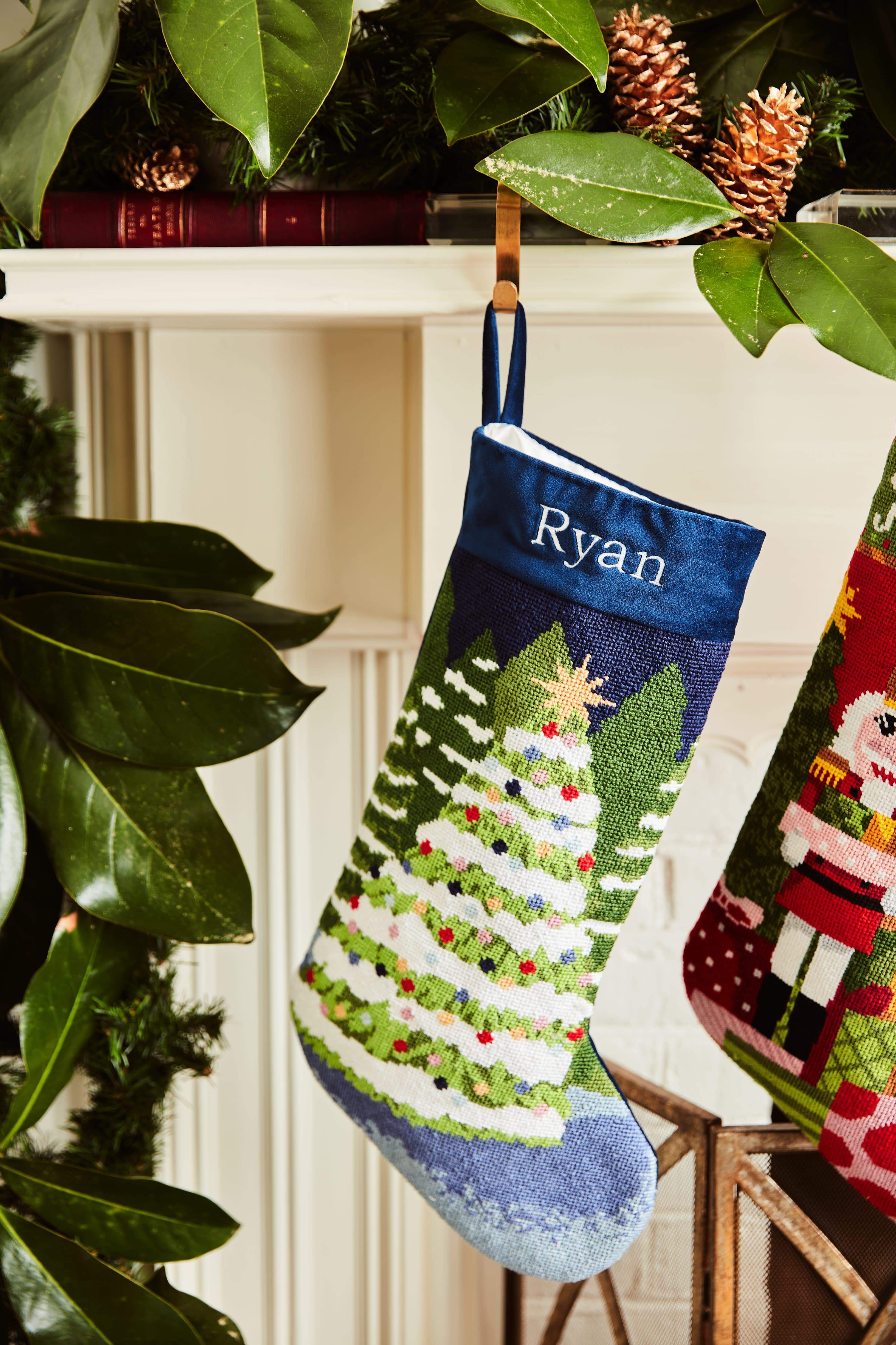 Full-size Christmas stocking with a monogrammed name in block featuring a snow-covered Christmas trees on a navy blue backdrop