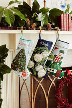 Festive mantle decorated with a Full Size Stockings, greenery, and holiday ornaments
