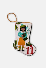 Hand-stitched Christmas stocking featuring piper in yellow and blue outfit with holly leaves on white backdrop