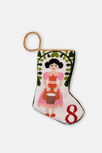 Hand-stitched stocking featuring milkmaid in pink and orange holding a pail, with greenery on a white backdrop