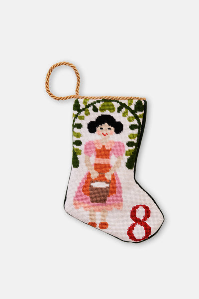 Hand-stitched stocking featuring milkmaid in pink and orange holding a pail, with greenery on a white backdrop