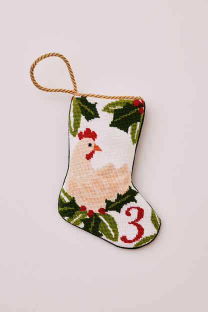 Needlepoint stocking featuring a hen with green holly accents on white backdrop