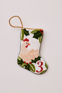 Needlepoint stocking featuring a hen with green holly accents on white backdrop