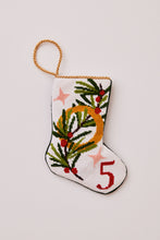 Needlepoint stocking featuring pine sprigs and a gold ring with festive stars on a white background