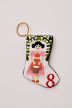 Hand-stitched stocking featuring milkmaid in pink and orange holding a pail, with greenery on a white backdrop