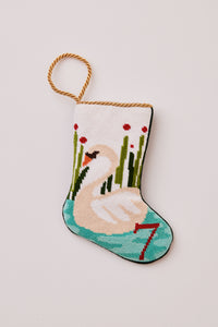 Hand-stitched stocking featuring an elegant swan swimming in the freshwater lake with cattails on a white backdrop