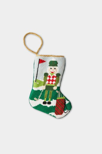 Hand-stitched needlepoint stocking with a sporty nutcracker on a golf course, dressed for festive tee time on a green fairway
