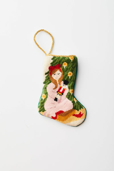 Hand-stitched needlepoint stocking featuring Clara in pink dress holding nutcracker with holiday greenery