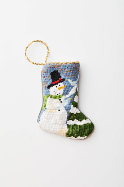 Frosty needlepoint stocking with smiling snowman in top hat and scarf, surrounded by snowy trees