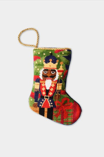 Christmas stocking featuring a Nutcracker in a vibrant uniform and golden crown, set against a backdrop of greenery and gift boxes.