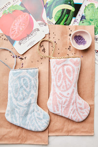 Holiday flatlay featuring Peace, Love, and Joy stockings in pink and blue