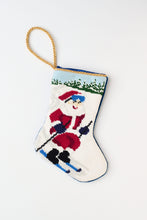 Christmas stocking featuring Santa skiing down a snowy hill with a red outfit against a snowy background